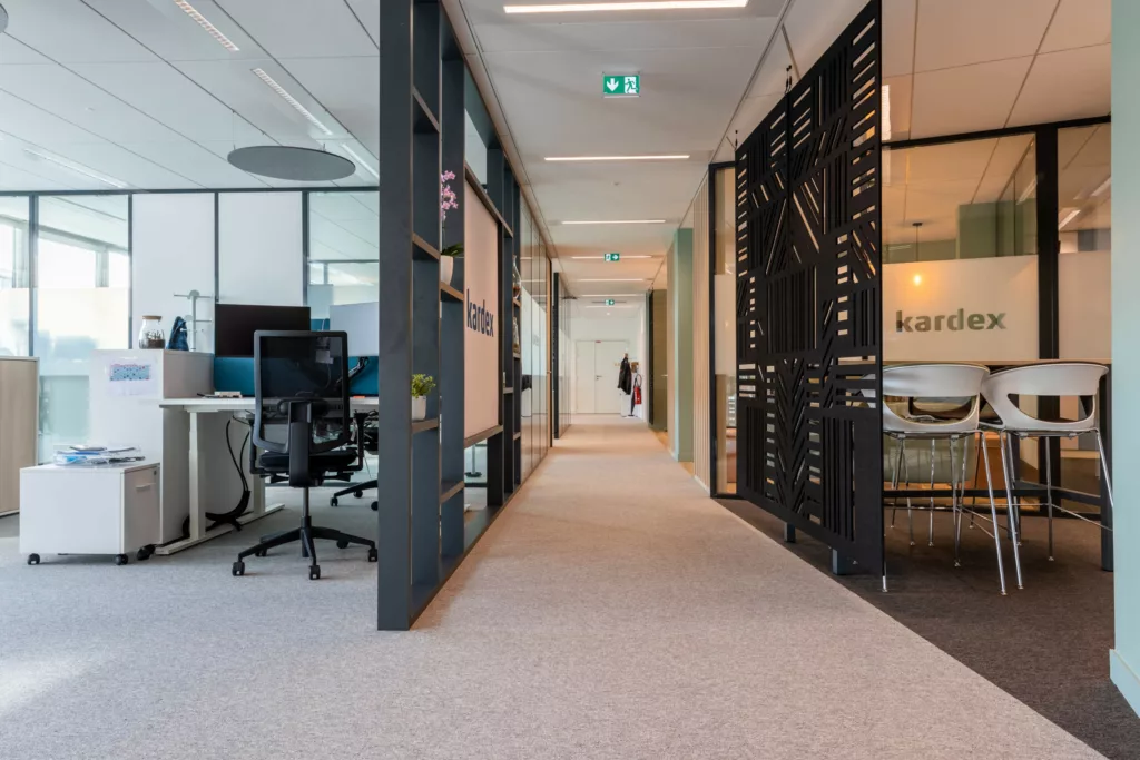 Couloir d'un plateau de bureaux aménagé avec moquette acoustique et séparations vitrées.