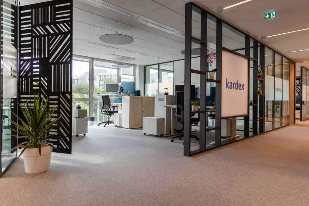 Panneaux acoustiques ajourés et signalétique sur un plateau de bureaux aménagé.