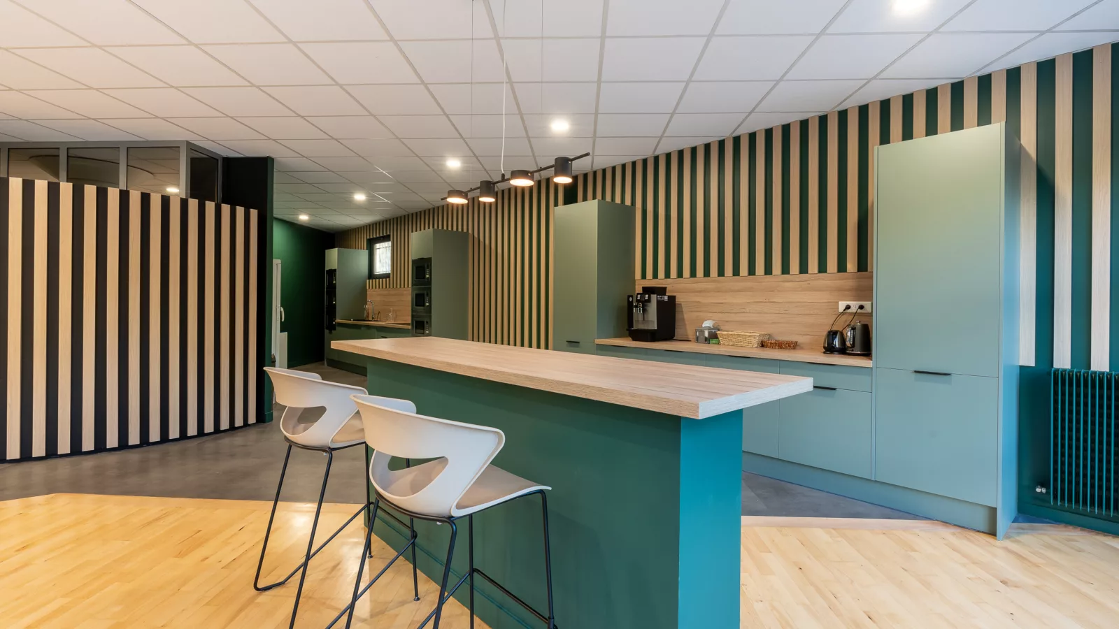 AMSO : Aménagement d'un espace repas/cuisine moderne avec mobilier de cafétéria, plan de travail et décoration murale dans les bureaux au Perray en Yvelines (78).