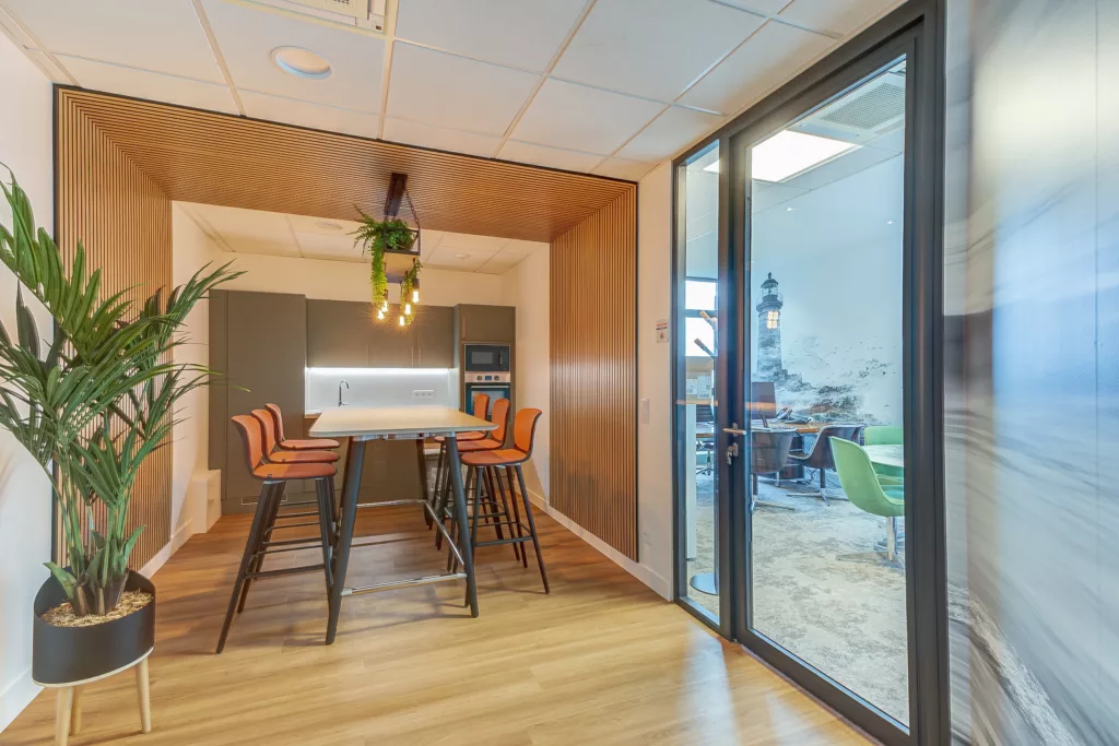 Aménagement de la kitchenette et de l'espace repas dans les bureaux de S3R à Noisy-le-Roi (78). Panneaux acoustiques en bois (tasseaux) et mobilier haut.