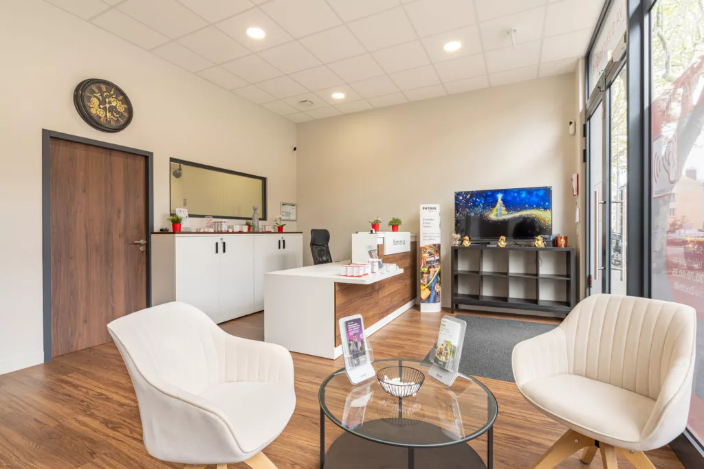 Aménagement de la zone d'accueil et d'attente d'un centre d'audioprothésiste à Viroflay (78). Mobilier moderne, banque d'accueil et décoration intérieure.