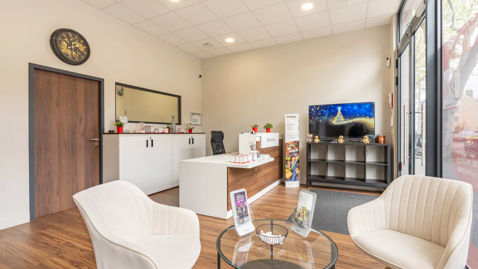 Aménagement de la zone d'accueil et d'attente d'un centre d'audioprothésiste à Viroflay (78). Mobilier moderne, banque d'accueil et décoration intérieure.