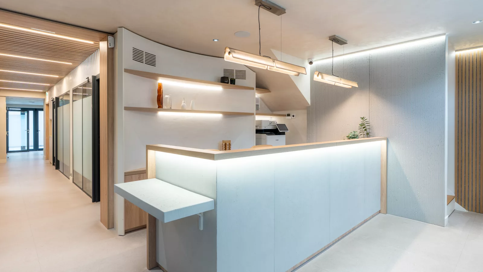 Banque d'accueil sur mesure pour cabinet dentaire et de chirurgie à Ivry-sur-Seine (94). Comptoir moderne avec éclairage LED intégré et étagères décoratives en bois