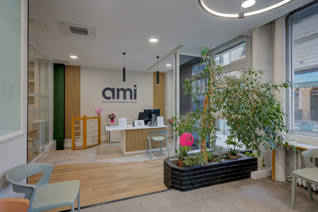 Salle d'attente et zone d'accueil du centre de santé AMI. Rénovation AMSO montrant la pose de sols PVC en courbe pour délimiter les espaces, un grand panneau acoustique décoratif et la banque d'accueil au fond