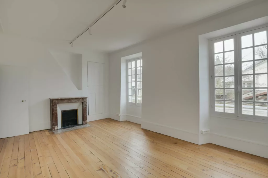 Aménagement d'un bureau de maire avec mobilier de direction haut de gamme, parquet massif et poutres anciennes conservées.