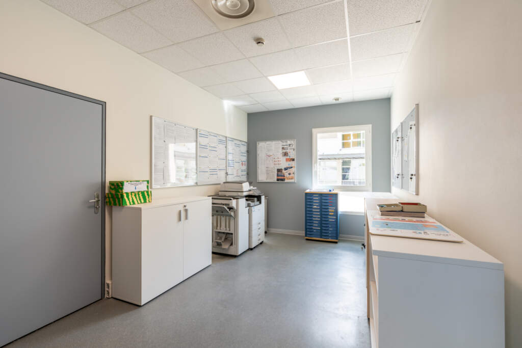 Local de reprographie et d'archives d'entreprise avec circulations larges adaptées aux déplacements en fauteuil roulant.