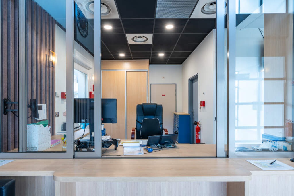 Guichet d'accueil vitré avec bureau ergonomique aménagé sur mesure pour un Établissement Recevant du Public.