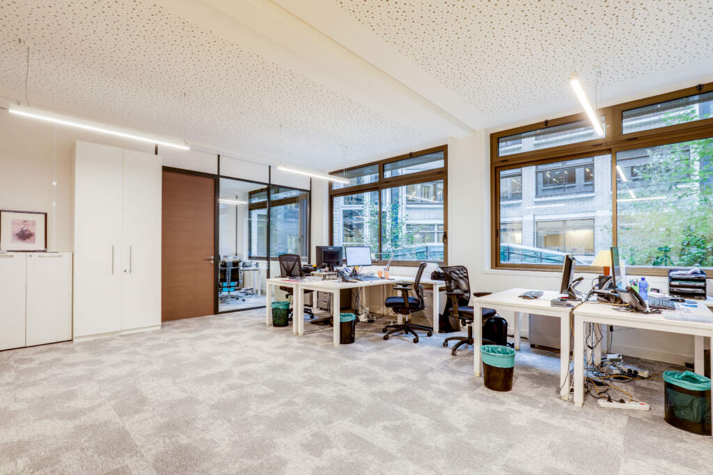 Bureaux open space modernes et lumineux aménagés avec cloisons vitrées et plafond acoustique par AMSO à Paris.