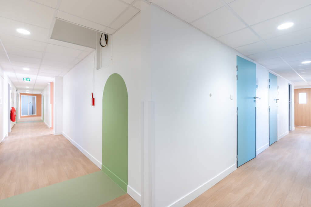 Couloir aux normes ERP avec portes de couleurs et signalétique visuelle.