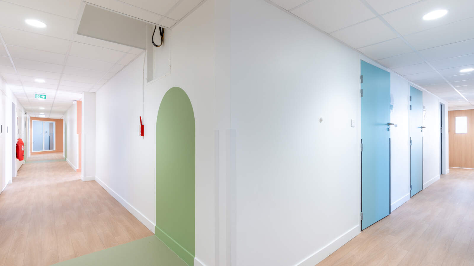 Couloir aux normes ERP avec portes de couleurs et signalétique visuelle.
