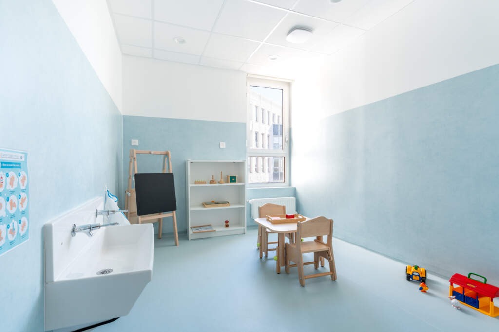 Salle d'éveil avec lavabo ergonomique et mobilier bois pour enfants.
