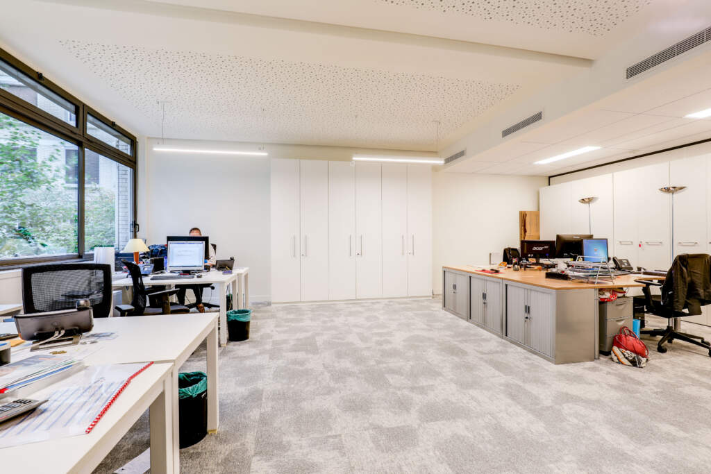 Grand espace de bureaux lumineux équipé de vastes armoires blanches et de meubles de rangement bas, projet AMSO.