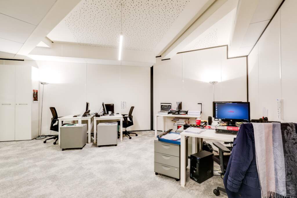 Espace de bureaux partagés avec bureaux blancs, rangements intégrés et dalles acoustiques au plafond, aménagement par AMSO.