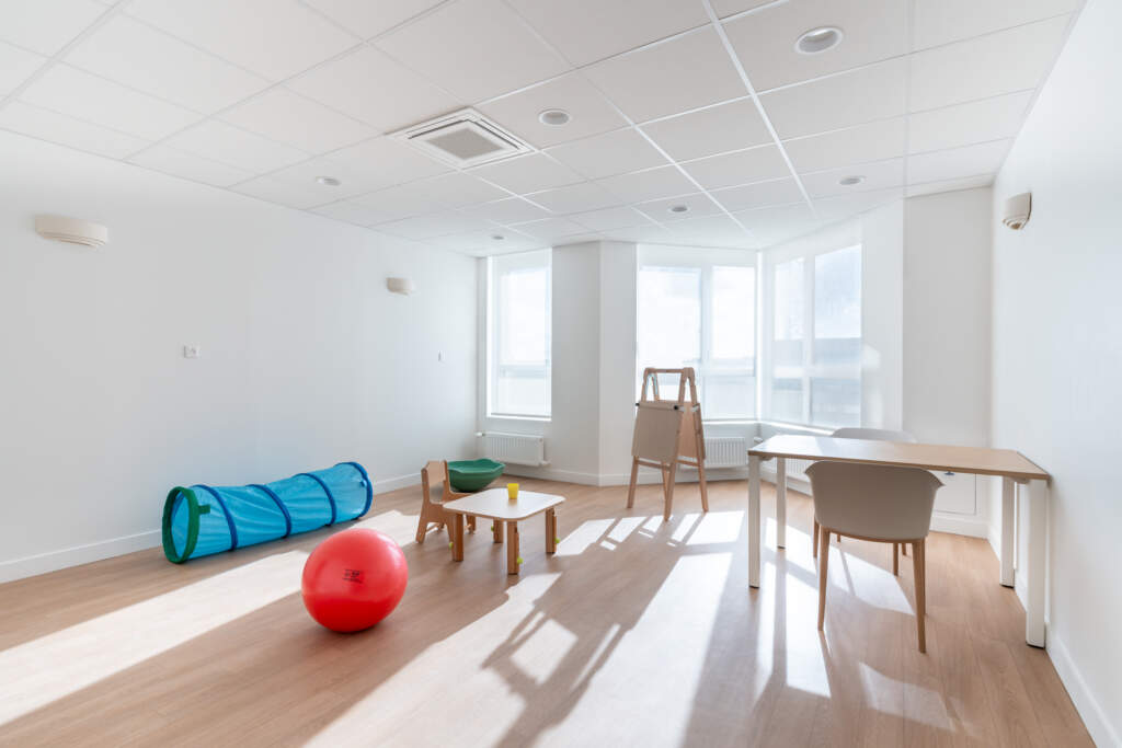 Salle de motricité pour enfants avec tunnel de jeu, ballons de thérapie et sol souple dans le centre GAPAS.