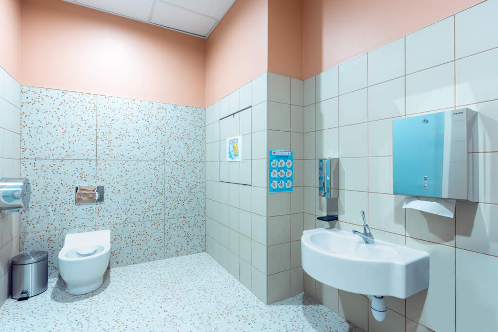Toilettes PMR avec carrelage terrazzo et équipements sanitaires suspendus.