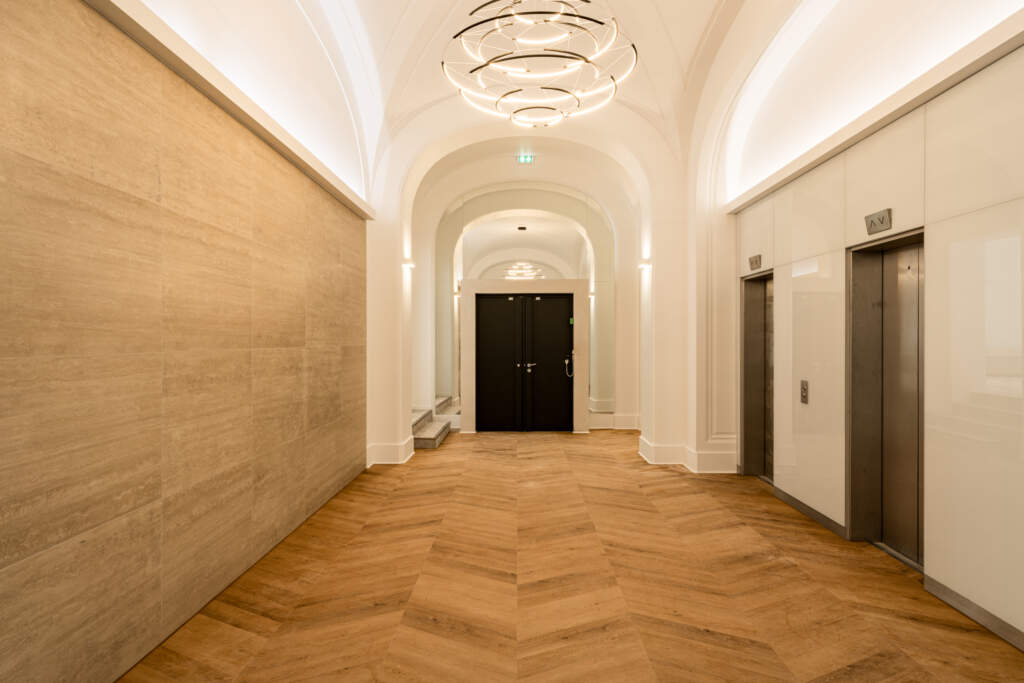 Hall de bureaux prestige avec lustre moderne et ascenseurs design - Paris