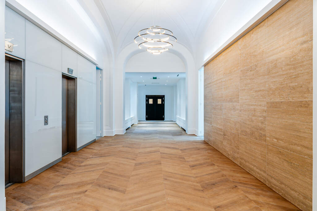 Aménagement hall d'accueil de luxe avec mur en pierre et parquet - Paris 16