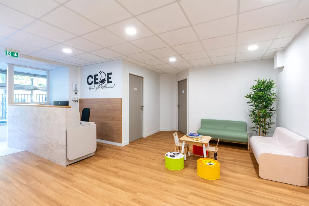 Espace d'accueil lumineux d'un centre médical pédiatrique avec comptoir sur-mesure et zone d'attente pour enfants.