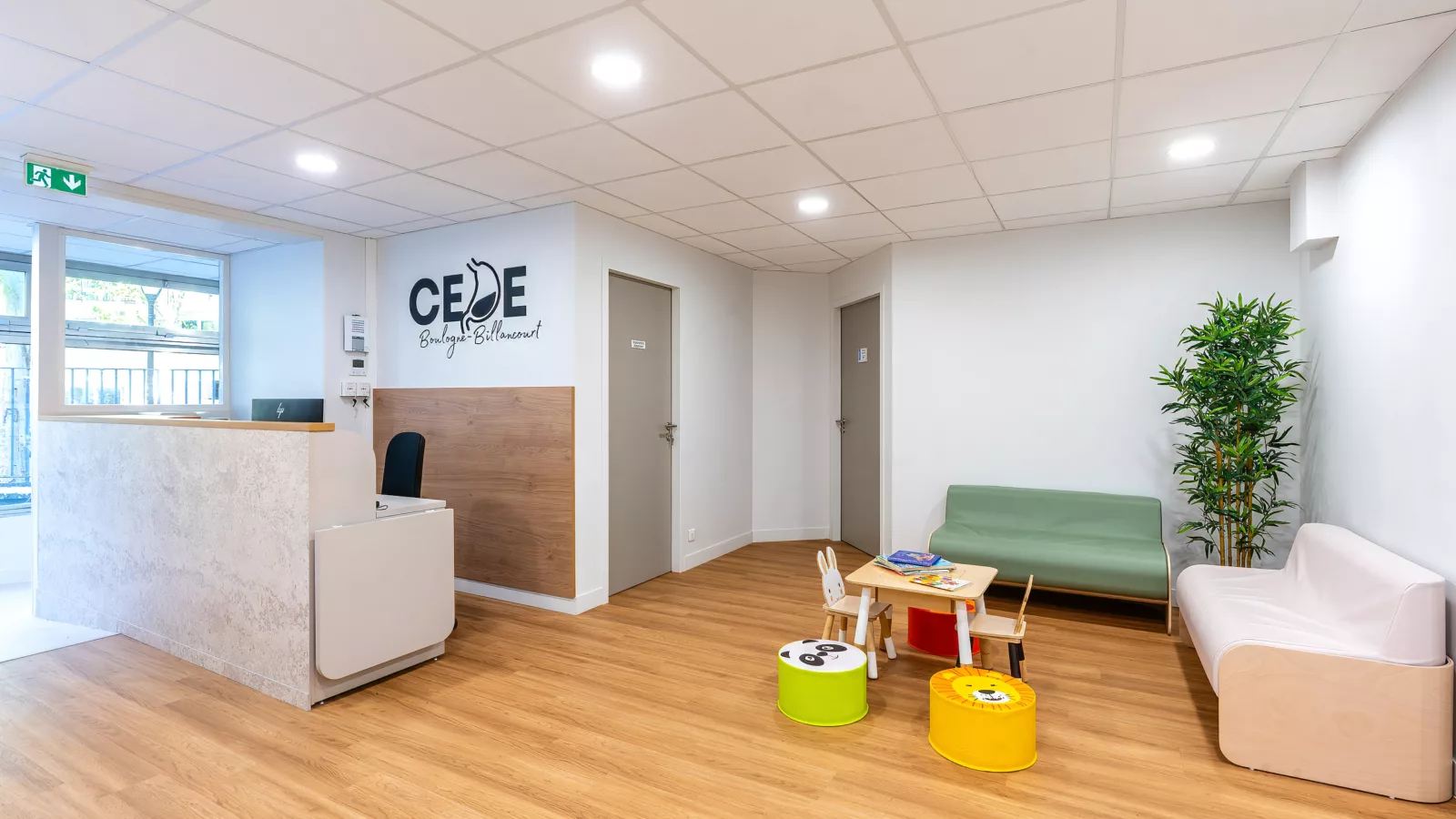 Espace d'accueil lumineux d'un centre médical pédiatrique avec comptoir sur-mesure et zone d'attente pour enfants.