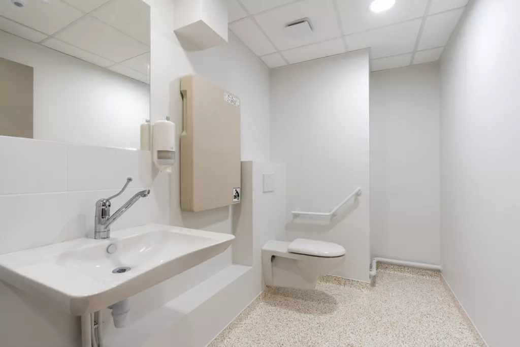 Sanitaires accessibles aux personnes à mobilité réduite (PMR) avec barres d'appui, espace de manœuvre et table à langer.