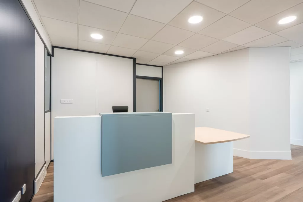 Banque d'accueil PMR sur mesure en bois et stratifié gris installée par AMSO dans un cabinet de santé en Île-de-France.